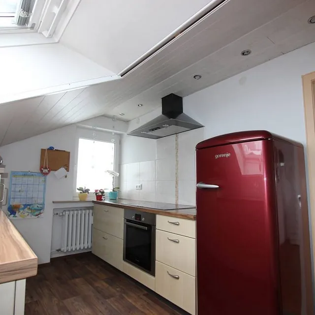 Gemütliche Küche mit rotem Kühlschrank und einem schönen Holztisch, ideal für gesellige Zusammenkünfte.