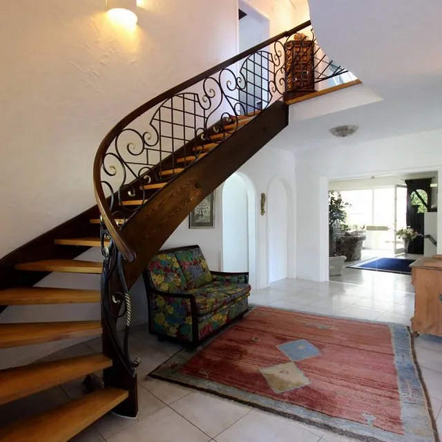 Eine einladende Treppe in einem Zuhause, umgeben von einem Teppich und gemütlichen Stühlen, strahlt Wärme und Komfort aus.