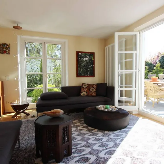 Gemütliches Wohnzimmer mit großem Fenster und einladender Couch, die Licht und Komfort vereint.